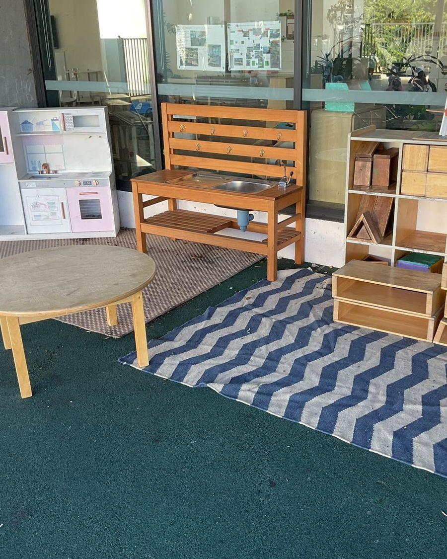 A play kitchen, shelves and a round table in a Blooming Buds play space