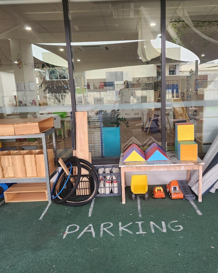 Wooden shelves with blocks and loose parts beside the Blooming Buds play room windows
